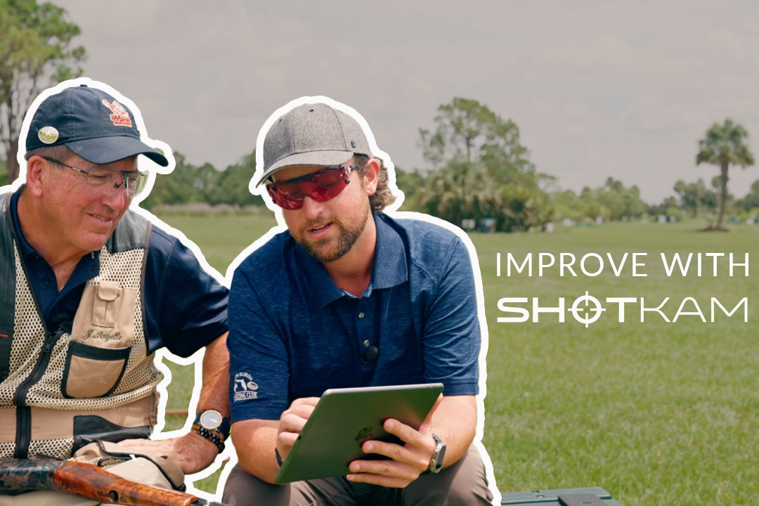 Shooting improvement in the UK: Two shooters reviewing ShotKam footage on a tablet, discussing tips for better accuracy.
