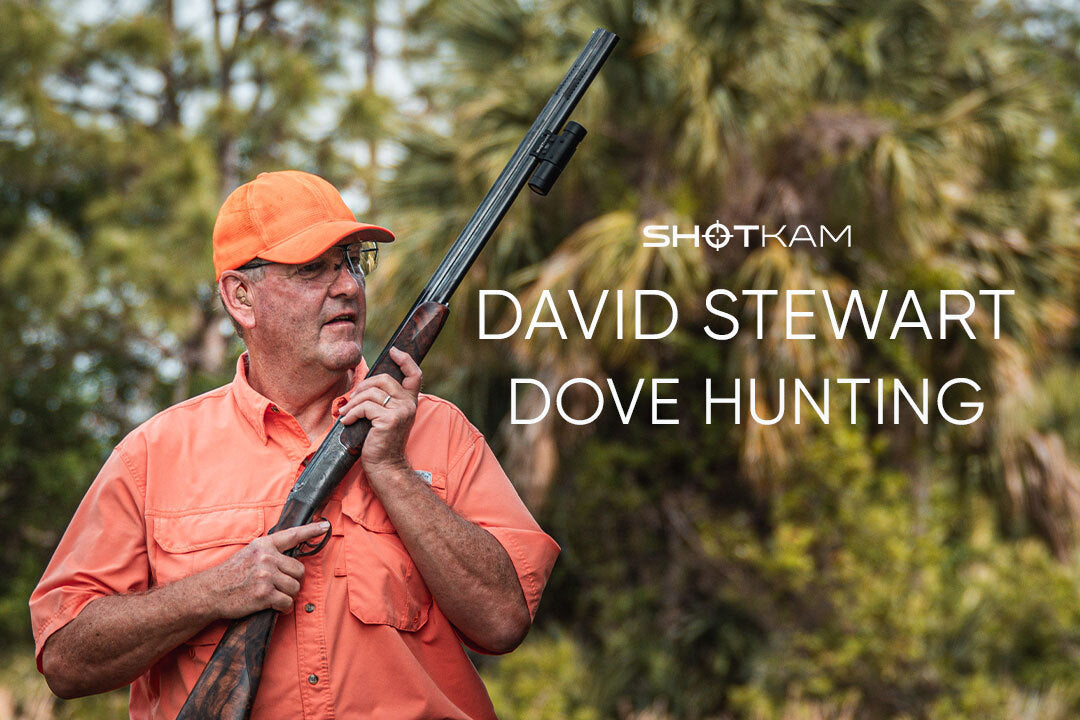 Hunter in orange cap and shirt carrying shotgun with ShotKam camera, blog thumbnail for dove hunting.