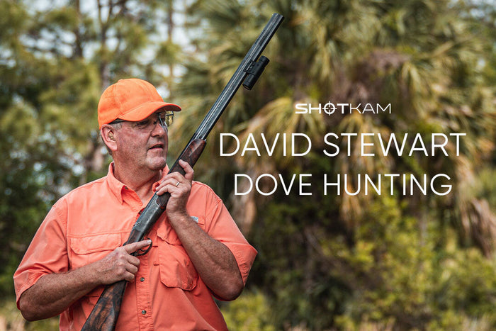 Hunter in orange cap and shirt carrying shotgun with ShotKam camera, blog thumbnail for dove hunting.